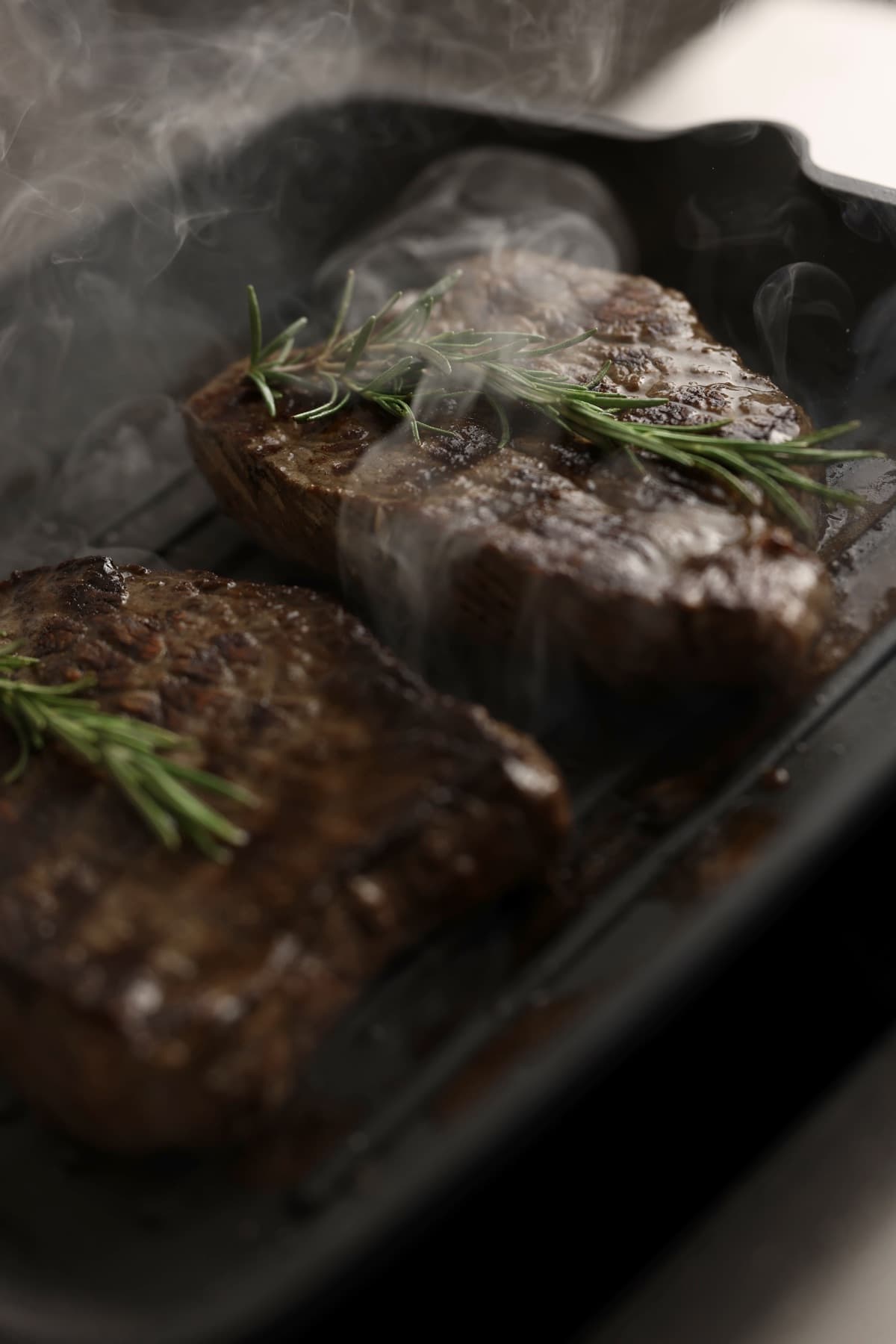 Saftiges, grilliertes Steak mit frischen Kräutern auf Holzbrett, Ausdruck für authentischen Genuss und Qualität.